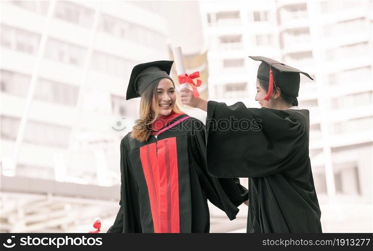 Two asian female students wearing uniform, cap and smiling with happiness after graduation. Education Concept.