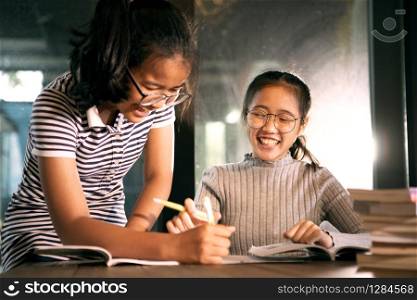 two asian girl laughing with happiness emotion doing school home work in living room