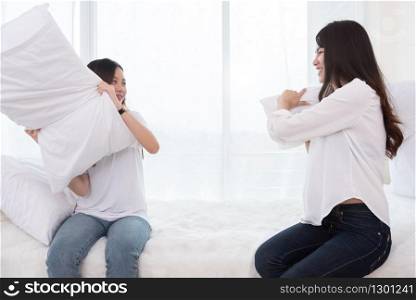 Two Asian girls doing pillow fight in bedroom as childhood. Lifestyles and People concept. Relation and friendship theme. Couple and friends concept. LGBT and people lifestyle
