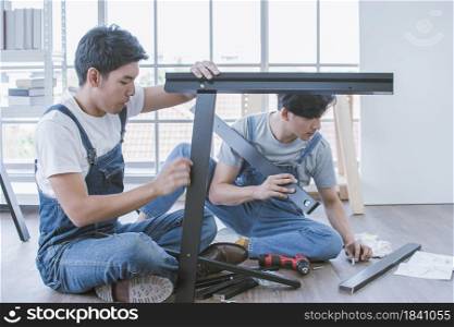 Two asian handsome men are helping together for making furniture assembly