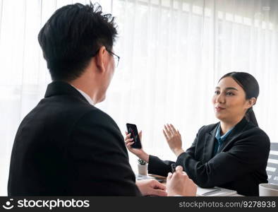 Two Asian office workers discussing and working together in corporate office workplace. Coworkers smiling and planning business work in friendly working environment in corporate workspace. Jubilant. Two Asian office workers working together in workplace. Jubilant