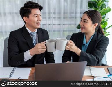 Two Asian office workers taking coffee break together in workplace. Coworkers smiling and socializing while holding cup of coffee adding friendly working environment in corporate workspace. Jubilant. Two Asian office workers taking coffee break together in workplace. Jubilant