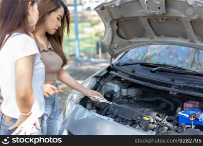 Two Asian people try to check the car engine and wait for assistance after a car breakdown on street. Concept of a vehicle engine problem or accident and emergency help from a Professional mechanic