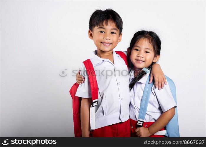Two Asian student kid girl boy schoolchildren brother sister smile happy wear student thai uniform red pants skirt hug each other isolated on white background, Portrait little children girl preschool