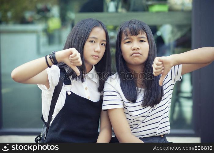 two asian teenager hand sign thumb no good with not satisfy face