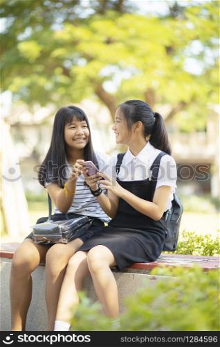 two asian teenager happiness face holding smartphone in hand talking wiht relaxing emotion