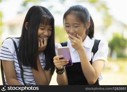 two asian teenager laughing with happiness face reading message in smart phone screen