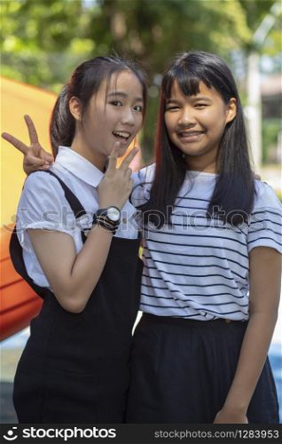 two asian teenager smiling face and raising victory hand
