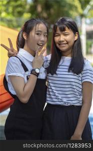 two asian teenager smiling face and raising victory hand
