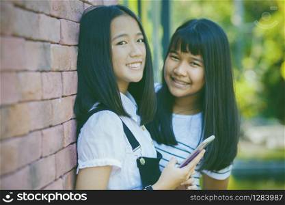 two asian teenager toothy smiling face with happiness emotion holdhing smartphone in hand