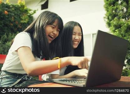 two asian teenager typing on computer labtop happiness emotion