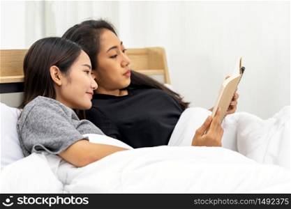 Two Asian university woman reading book at home in bedroom for studying while School shutdown due to city lockdown from COVID-19 Pandemic. Education online and study at home concept.