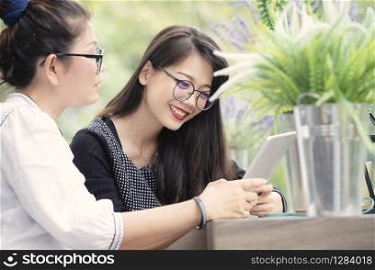 two asian woman with smart phone in hand talking in home living room with happiness face