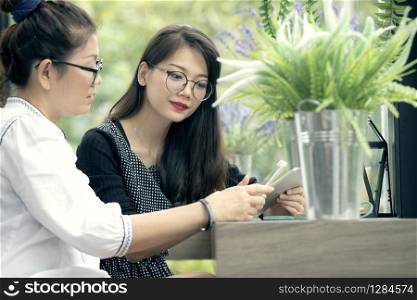 two asian woman with smart phone in hand talking in home living room with happiness face