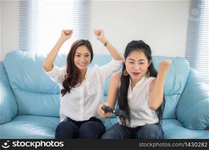 two Asian women Competitive friends playing video games and excited happy cheerful at home
