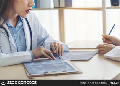 Two asian women doctors discuss meeting doctor&rsquo;s office medical clinic looking x-ray film consulting patient disease. Asian medical lab young women talking together discussing healthcare teamwork