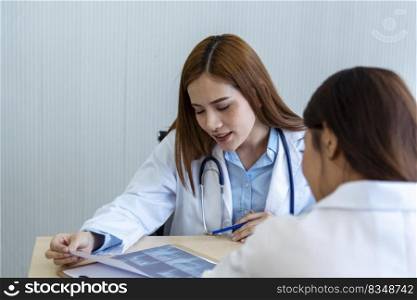 Two asian women doctors discuss meeting doctor&rsquo;s office medical clinic looking x-ray film consulting patient disease. Asian medical lab young women talking together discussing healthcare teamwork