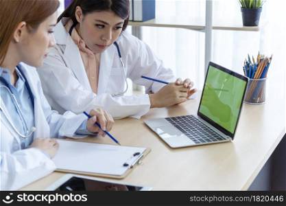 Two asian women doctors discuss meeting doctor&rsquo;s office medical clinic using laptop consulting patient disease. Asian medical lab young women talking together discussing healthcare assistance teamwork