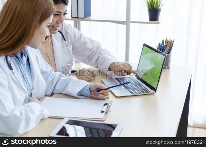 Two asian women doctors discuss meeting doctor&rsquo;s office medical clinic using laptop consulting patient disease. Asian medical lab young women talking together discussing healthcare assistance teamwork