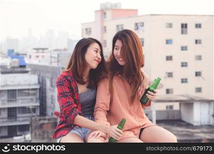 Two asian women drinking at rooftop party, outdoors celebration, friendship, LGBT couple
