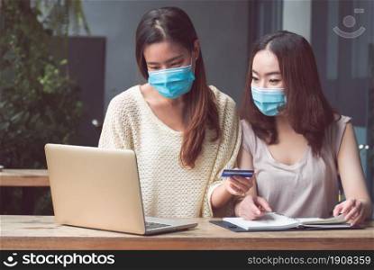Two asian women holding blank credit card to make payment for online shopping at home. Health, Commerce and Finance Concept