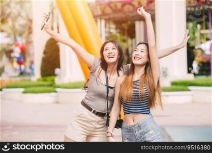Two Asian women relax casual happy smiling enjoy at amusement park outdoors.