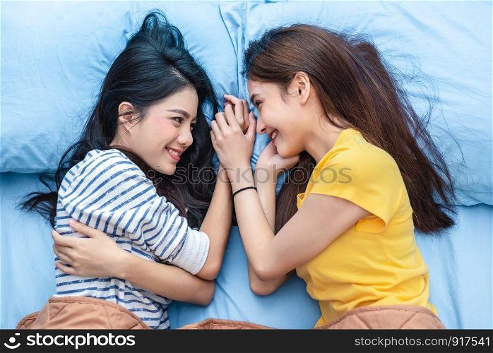 Two Asian womens looking at each others when lying on bed. Lifestyles and lovers concept. Happiness life and relax concept. Homosexual life theme. LGBT pride and lesbian couples theme.