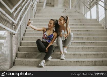 Two athlete women resting and taking selfie after jogging in urban enviroment