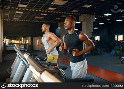 Two athletes runs on treadmill, training in gym. Fit workout in sport club, healthy lifestyle, fitness