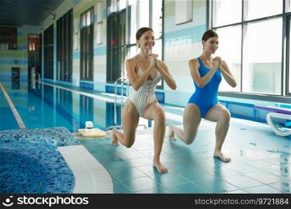 Two athletic sportive woman doing training workout before swimming at indoor pool. Group gymnastics course and aqua aerobics class concept. Two athletic sportive woman doing training workout before swimming