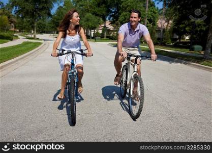 Two attractive adults, man and woman couple, cycling together.