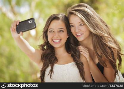 Two Attractive Mixed Race Girlfriends Taking Self Portrait with Their Phone Camera Outdoors.