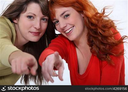 Two attractive women pointing fingers