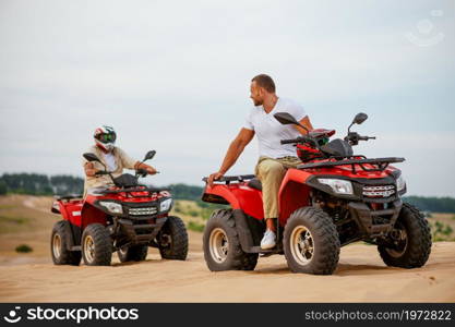 Two atv riders racing in desert sands. Male persons on quad bikes, sandy race, dune safari in hot sunny day, 4x4 extreme adventure, quad-biking concept. Two atv riders racing in desert sands
