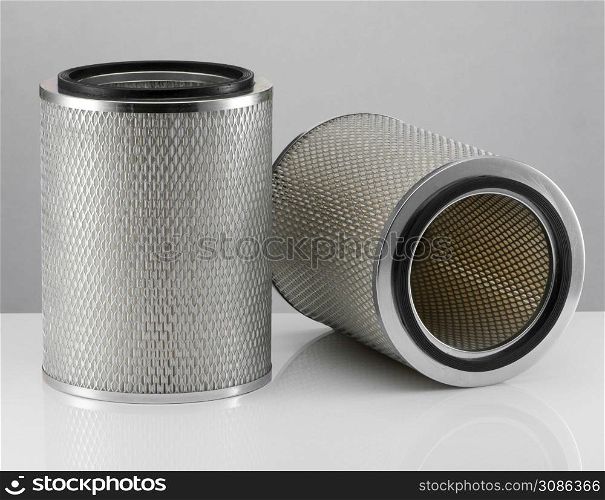 two automotive filter cylindrical shape on a white background with reflection. automobile filter on a white background