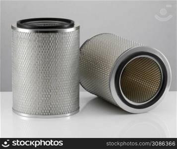 two automotive filter cylindrical shape on a white background with reflection. automobile filter on a white background