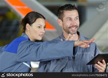 two aviation engineers holding tablet and pointing forwards