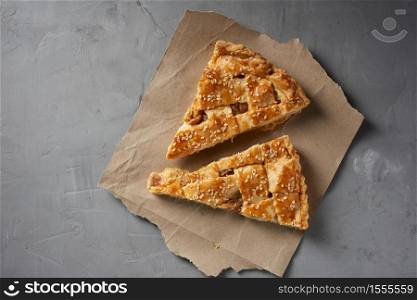 two baked pieces of apple pie on brown paper, top view, gray background