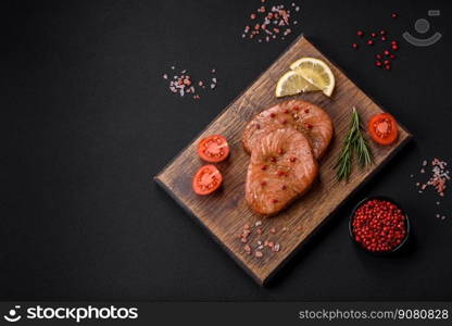 Two baked slices of tuna fillet with spices and herbs on a dark concrete background