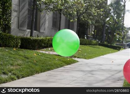 Two balloons flying over a walkway