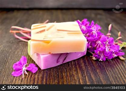 Two bars of homemade soap with fireweed flowers on the background of wooden boards