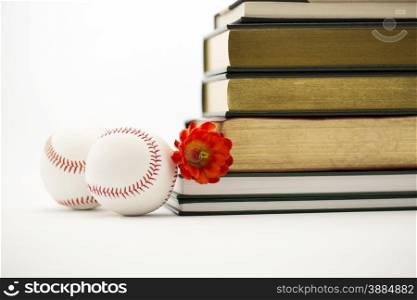 Two baseballs placed with red flower and stack of books depicts positive union of sports and education