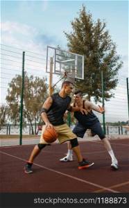 Two basketball players set up a match on outdoor court, active leisure. Male athletes in sportswear play the game on streetball training