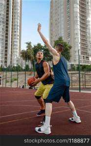 Two basketball players work out tactics on outdoor court. Male athletes in sportswear play the game on streetball training. Two basketball players work out tactics outdoor