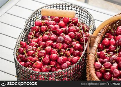 two baskets filled with beautiful red cherries on a garden table