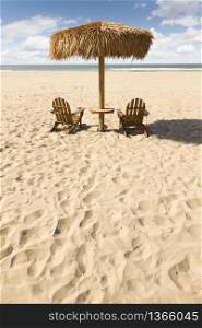 Two Beach Chairs and Umbrella on a Beautiful Ocean Front with Copy Space.