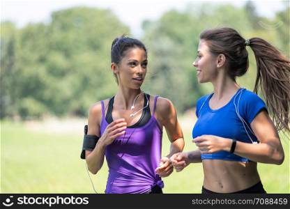 Two beautiful and attractive fitness girls are jogging in the park on a sunny morning
