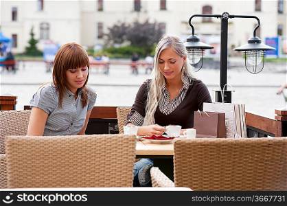 Two beautiful and sophisticated young women friends having coffee ia a city cafe