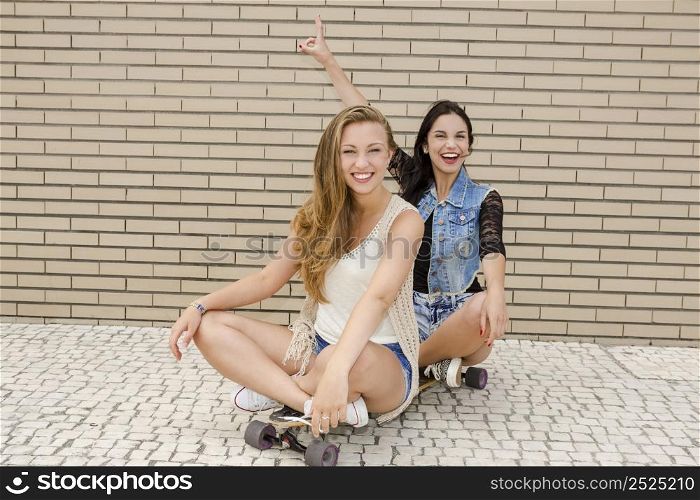 Two beautiful and young girlfriends having fun with a skateboard