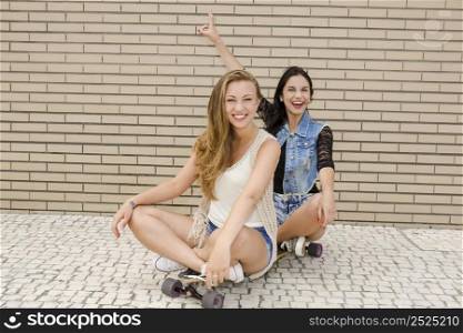 Two beautiful and young girlfriends having fun with a skateboard